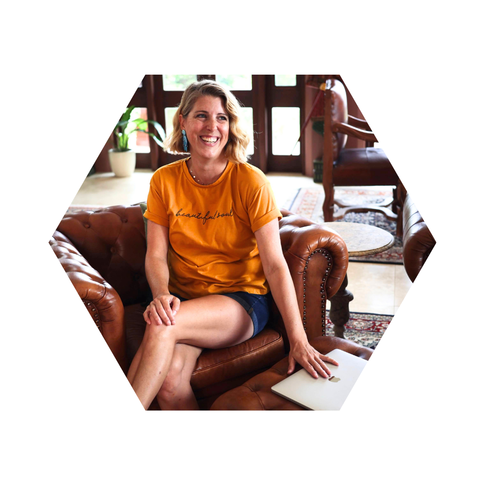 georgina dawkins sitting on a chair smiling with her hand on an apple laptop